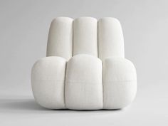 a white chair with four pillows on it's back and the seat upholstered