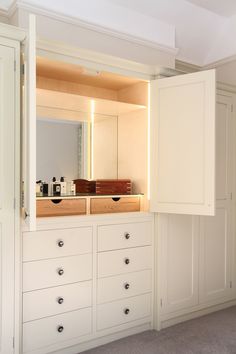 an empty room with white cabinets and drawers on the wall, in front of a mirror