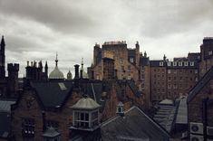 an old city with tall buildings and steeples under a cloudy sky in the foreground