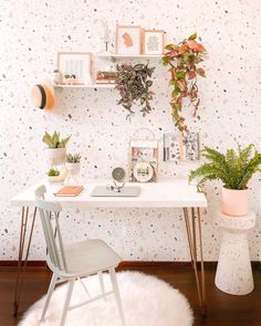 a white desk with some plants and pictures on it