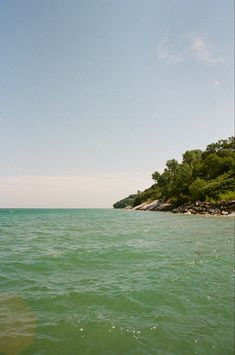 the water is very green and blue with some trees in the backgrouds