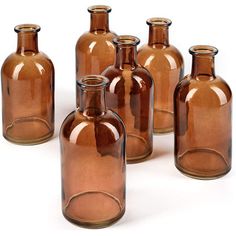 six brown glass bottles are lined up in a row and one is empty, the other has no lid