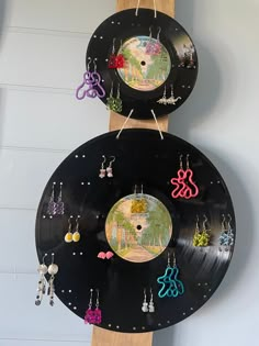 two records are hanging on the wall with earring holders attached to them, and one is made out of black vinyl