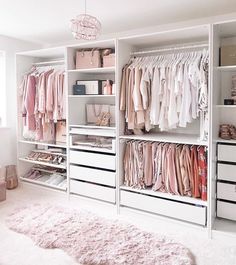 a white closet filled with lots of pink and white clothes on top of wooden shelves