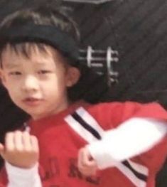 a young boy holding a white frisbee in his right hand and wearing a red shirt