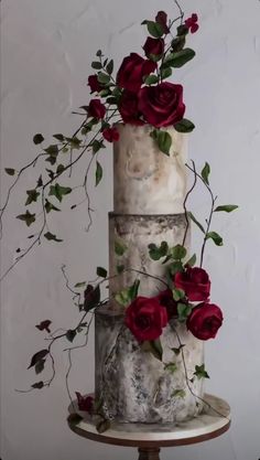 a three tiered cake with red roses on top