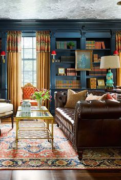 a living room filled with furniture and bookshelves next to a window covered in curtains