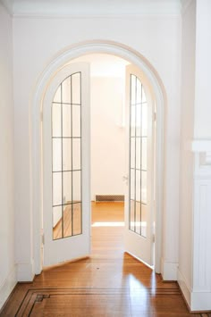 an open door leading to another room with wooden floors and white walls, along with hardwood flooring