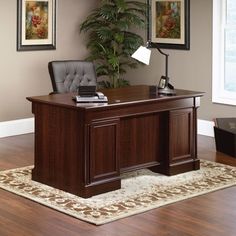 an office desk with a chair, lamp and rug