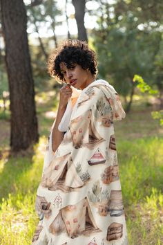 a woman is standing in the woods with a blanket over her head and eating something