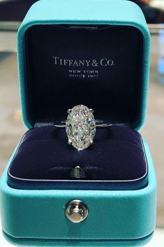 an oval cut diamond ring in a blue velvet box with the words tiffany & co on it