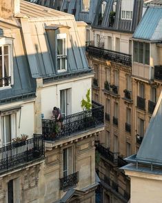 a man is standing on the balcony of an apartment building in paris, looking out at the surrounding buildings