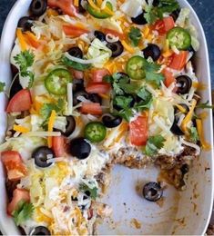 a casserole dish filled with black olives, peppers, cheese and other toppings