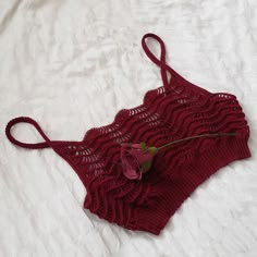 a crocheted bra with a rose attached to the side on a white sheet