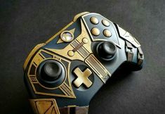 a close up of a controller on a black surface with gold trimmings and buttons