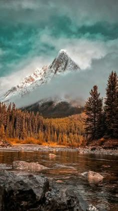 a mountain covered in snow sitting next to a river