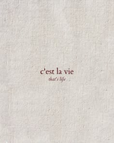 the words cest la vie are written in red ink on a white linen background