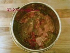 a pot filled with meat sitting on top of a wooden table