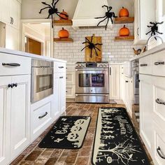 a kitchen decorated for halloween with pumpkins and spider web rugs on the floor