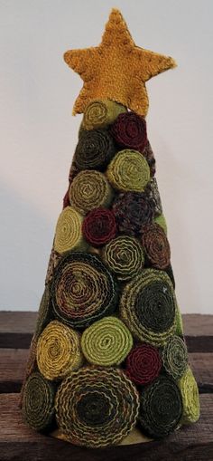 a small christmas tree made out of rolled up yarn with a gold star on top