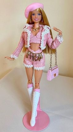 a barbie doll dressed in pink and white holding a handbag with her right hand