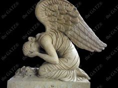 an angel statue sitting on top of a stone block