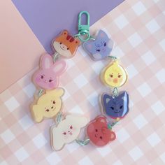 a bunch of cute animal shaped key chains on a checkered tablecloth with pink and purple background