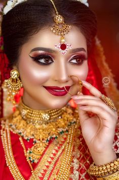 a woman in red and gold makeup looks like she is getting ready for her wedding