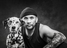 a man and his dog pose for a black and white photo in front of a dark background