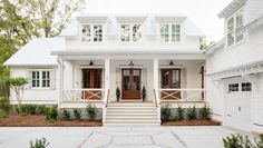 a white house with red front doors and steps leading up to the front door is shown