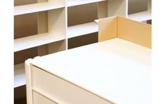 an empty white desk in front of some bookshelves with shelves on each side