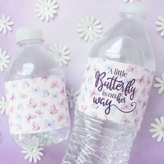 two plastic water bottles sitting next to each other on a purple surface with white flowers