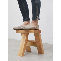 a woman standing on top of a wooden stool with her legs crossed and feet in the air