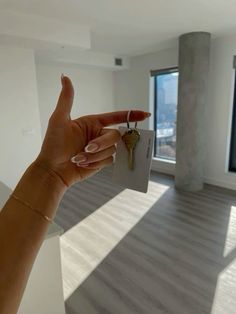 a hand holding a house key in front of a window