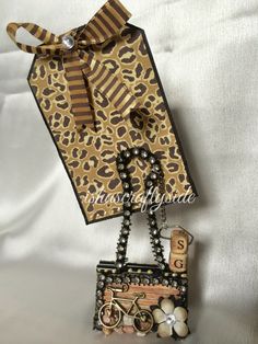 an animal print purse and keychain are hanging on a white sheet with the tag attached to it