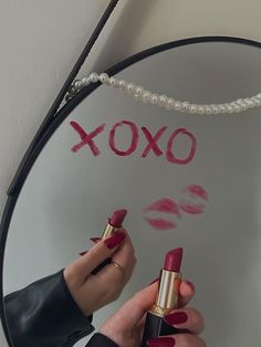 a person holding a lipstick in front of a mirror with the word xoxo written on it