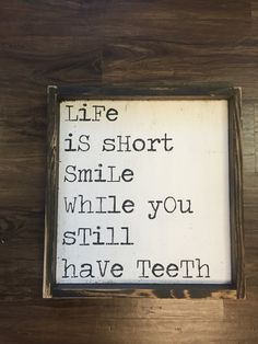 a wooden sign that says life is short smile while you still have teeth