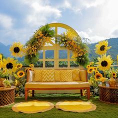 an outdoor seating area with sunflowers and potted plants on the grass, in front of a gazebo