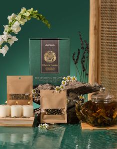 tea and candles on a table next to a green box with white flowers in it