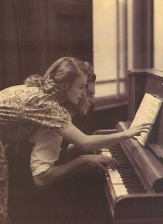 an old black and white photo of a woman playing the piano