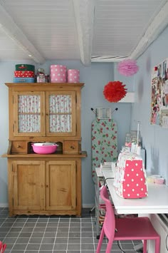 a kitchen with pink chairs and wooden cabinets in it's center area, next to a dining room table