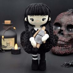 a knitted doll holding a hammer next to a skull and bottle with candles in the background