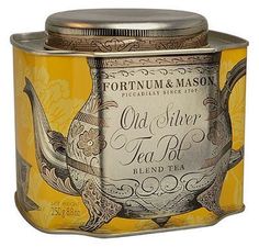 an old silver tea canister with a yellow lid and floral design on the side