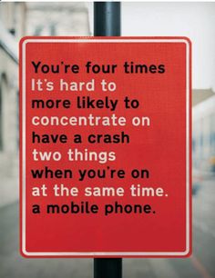 a red sign that reads you're four times it's hard to concentrate on have a crash two things when you're on at the same time a mobile phone