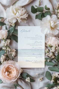 the wedding stationery is surrounded by flowers and greenery on top of a bed