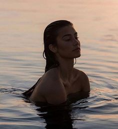 a woman is floating in the water with her head turned to the side and looking off into the distance