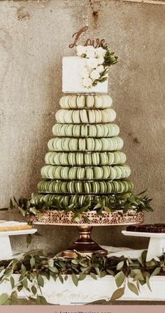 a wedding cake with macaroons and flowers on the top is surrounded by other desserts