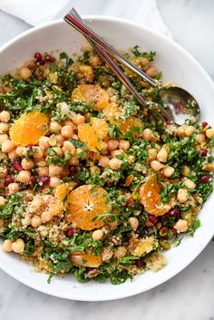 a white bowl filled with salad topped with oranges and chickpeas next to a spoon