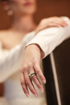 a woman in a white dress is holding her wedding ring