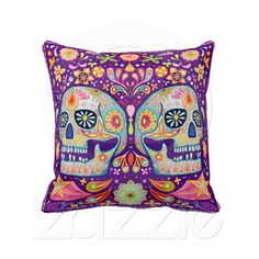 a decorative pillow with two skulls on it, one in purple and the other in orange